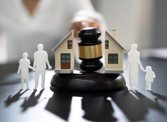 A gavel positioned between two model houses, symbolizing the legal management and transfer of real estate through a trust.